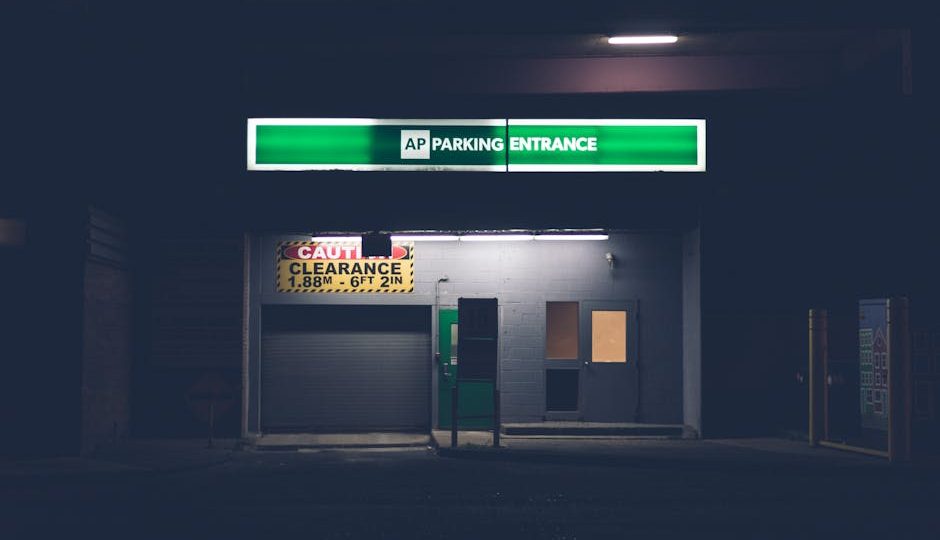 Entrada de estacionamento com iluminação automatizada e sinais luminosos à noite.