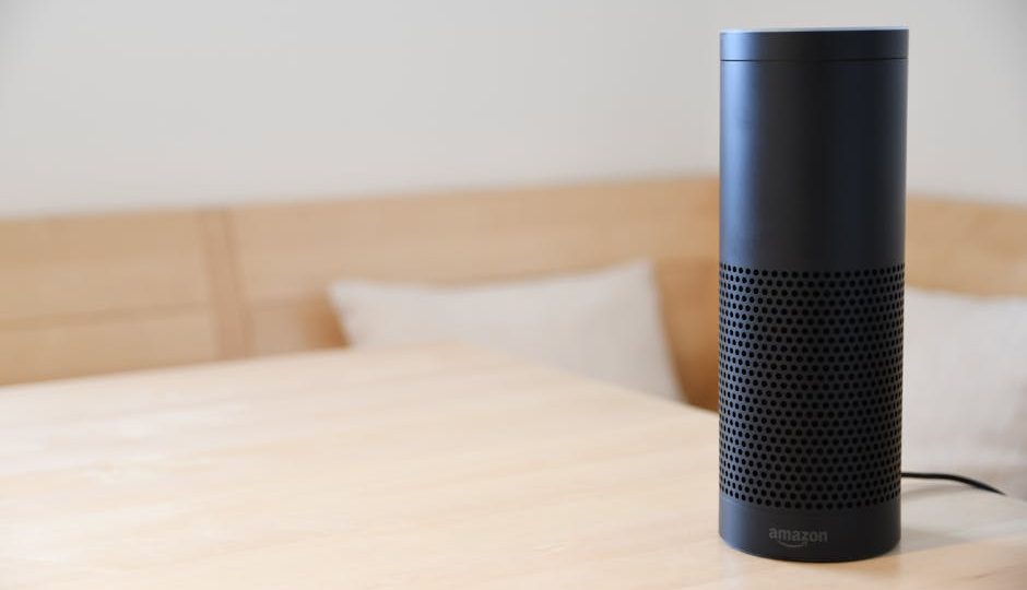 Um alto-falante inteligente preto descansando em uma mesa de madeira clara em um ambiente interno aconchegante.
