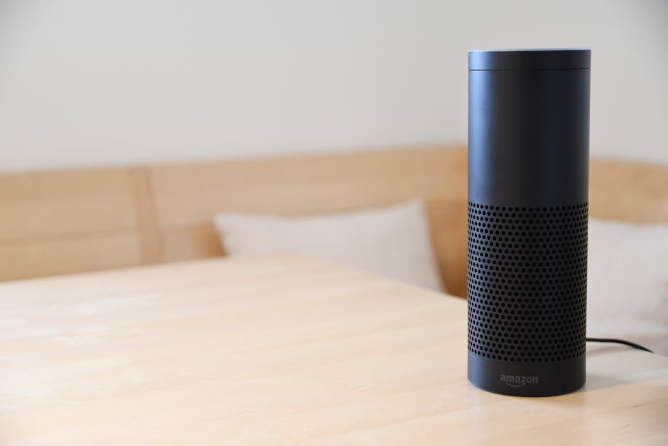 Um alto-falante inteligente preto descansando em uma mesa de madeira clara em um ambiente interno aconchegante.