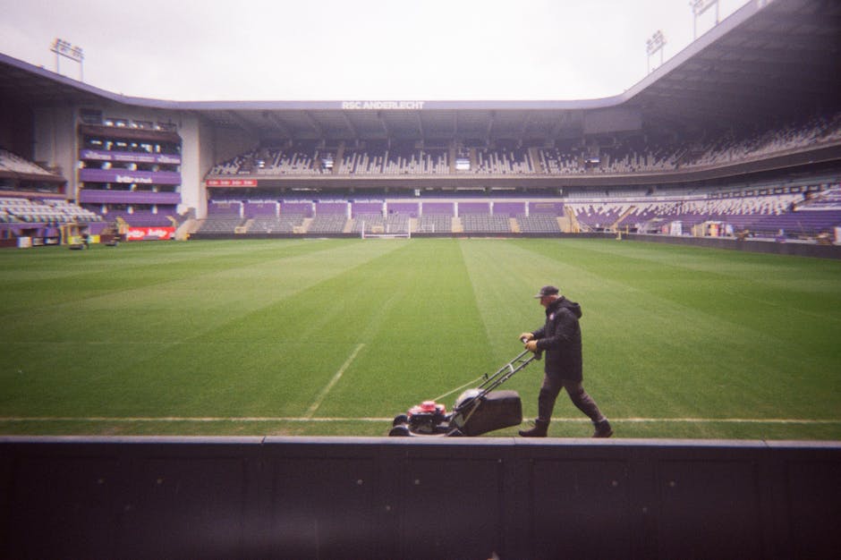 Funcionário corta a grama do estádio do RSC Anderlecht, se preparando para eventos esportivos.
