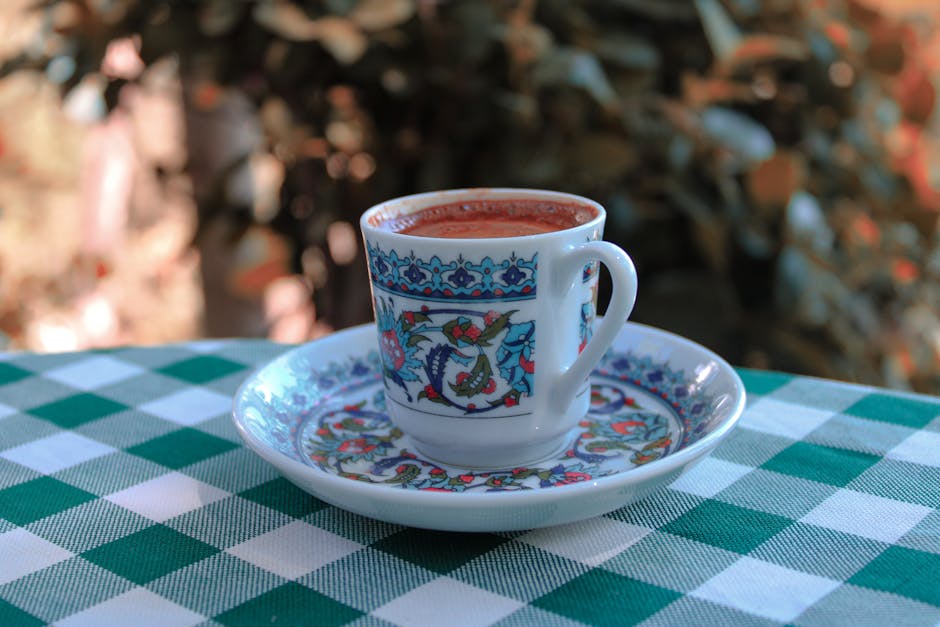 Xícara de chá em uma mesa de chá revelação, com padrões intricados, em um jardim.