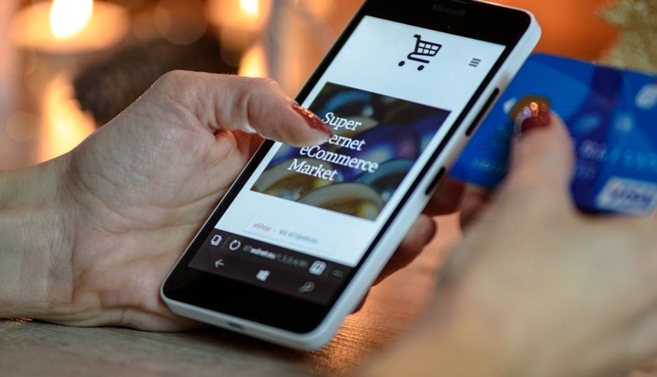 Mulher fazendo compras online pelo smartphone com cartão de crédito na mão, fundo iluminado festivo.