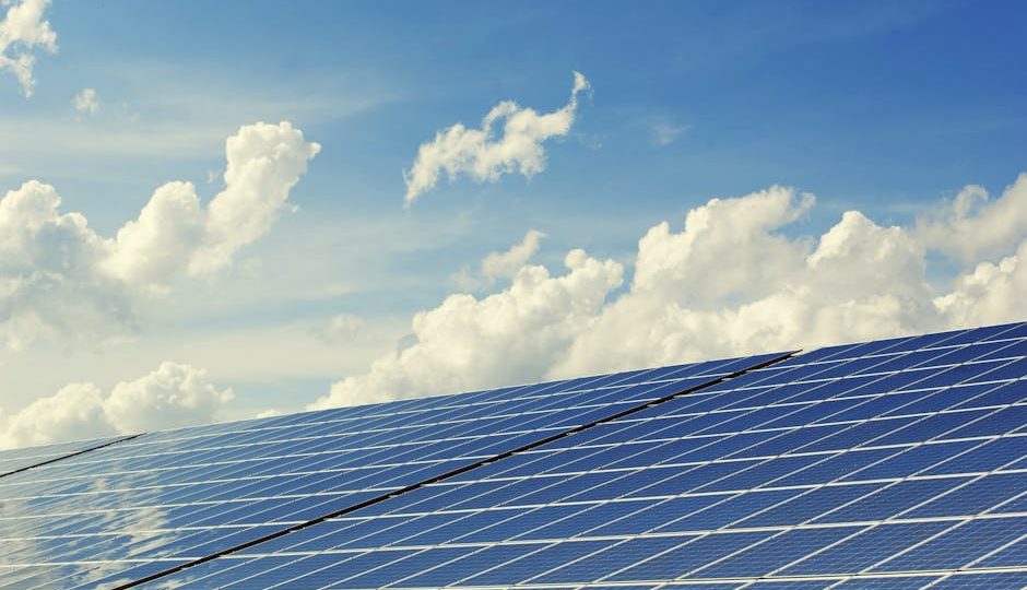 Painéis solares modernos sob um céu azul vibrante com nuvens, simbolizando energia limpa.