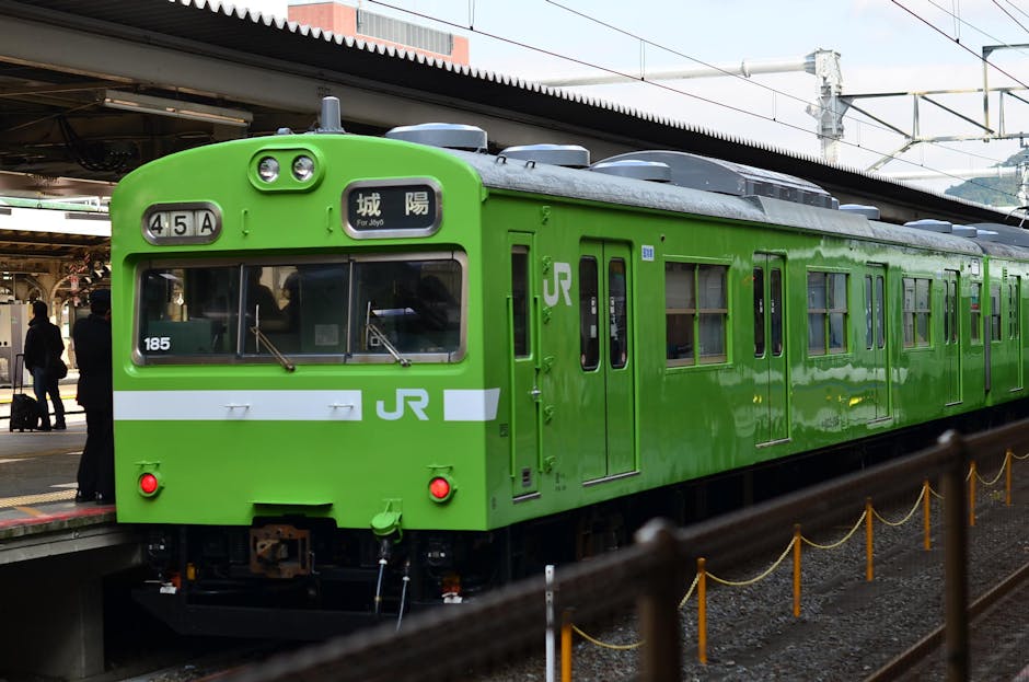 Um trem verde vibrante da JR parado na plataforma da estação de Kyoto, representando a eficiência do sistema ferroviário japonês.
