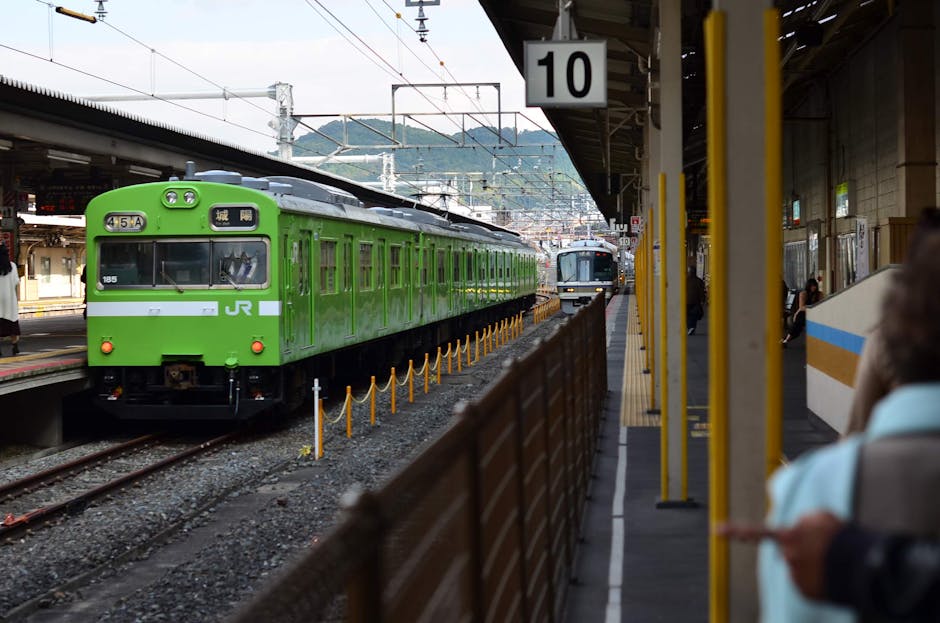 Um trem verde brilhante da JR chegando na estação movimentada de Kyoto em um dia claro.