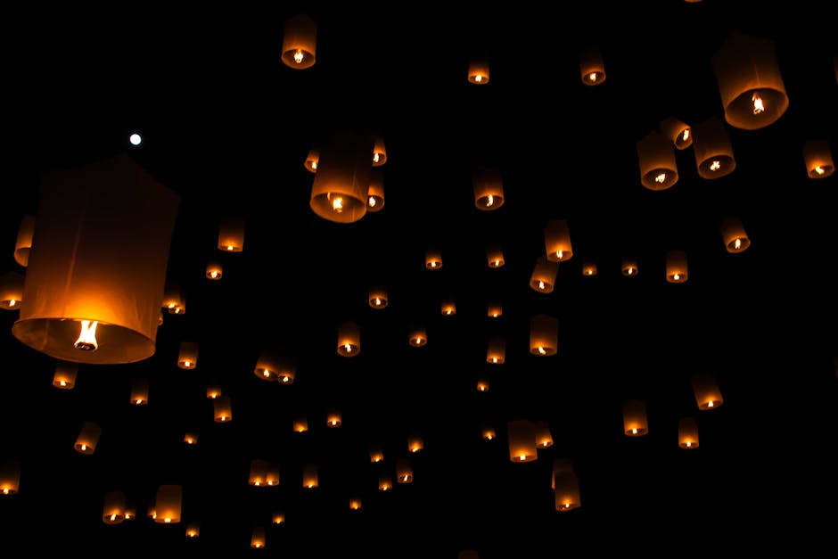 Lanternas flutuam no céu noturno durante festival tradicional na Tailândia.