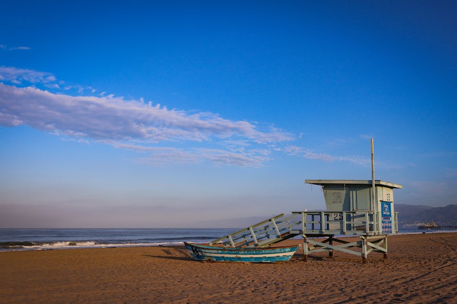 Anthony Gordon surfando em uma praia tranquila de Santa Monica, com céu azul e ondas suaves.