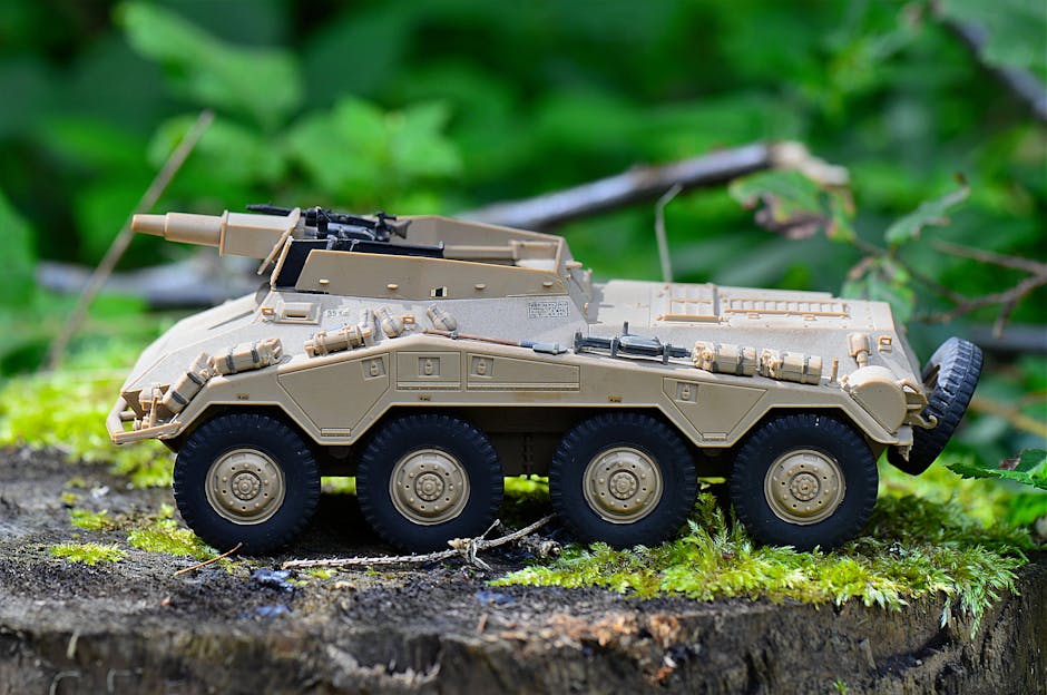 Miniatura de veículo blindado em cima de um tronco coberto de musgo, destacando design militar.