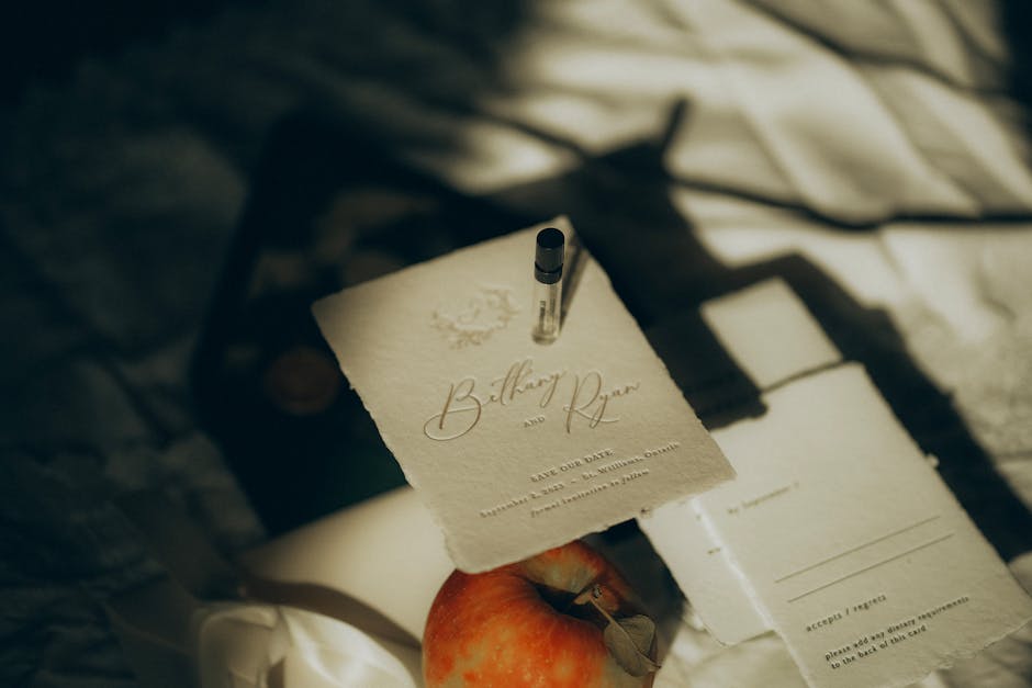 Foto de um cartão de save the date elegante com sombras suaves, uma maçã e um frasco de perfume, relacionado ao tema Bethany Quilos Mortais.