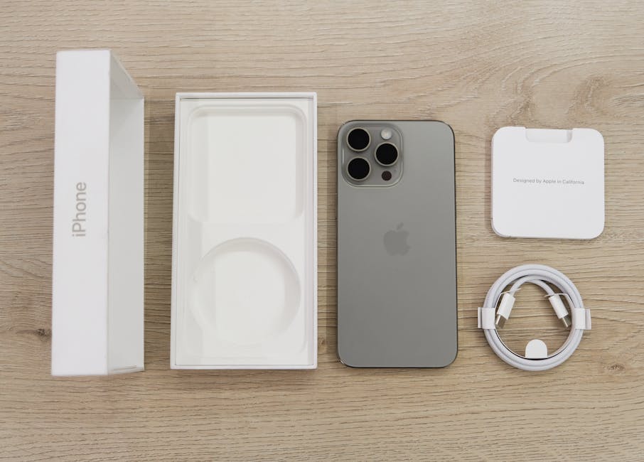 iPhone 16 Pro em cima de mesa de madeira, com caixa e acessórios de carregamento.