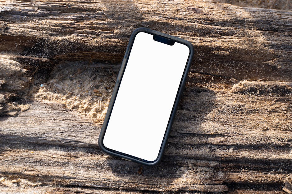 Mockup do iPhone 16 Pro com tela em branco em um tronco de madeira na Praia de Kamala, Phuket, Tailândia.