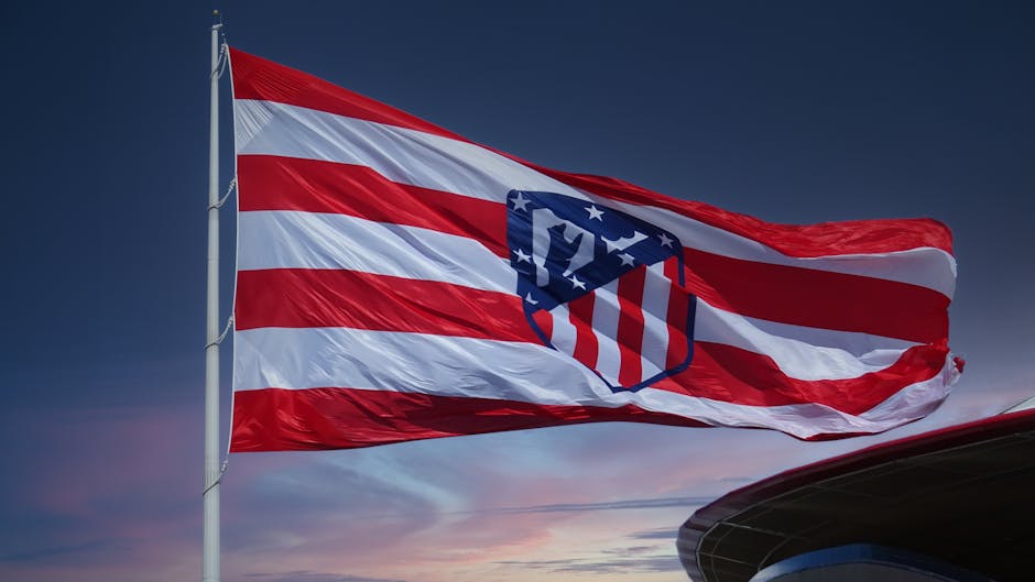 Bandeira do Atlético de Madrid tremulando em um pôr do sol, simbolizando o espírito da equipe em Madrid.