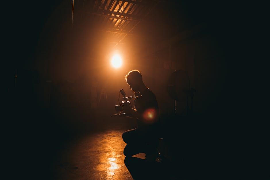Fotógrafo capturando a cena de um tapete vermelho com iluminação dramática em estúdio escurecido.