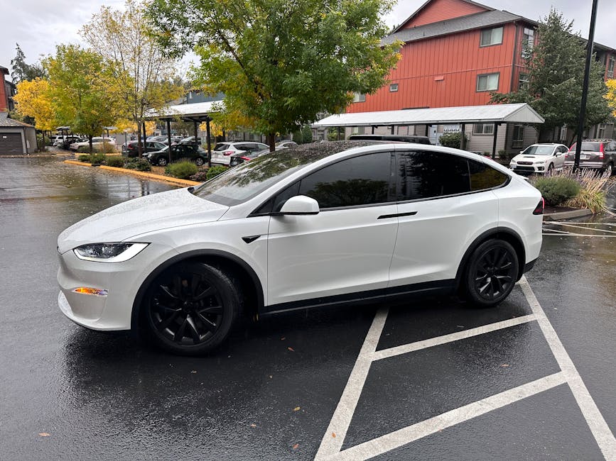Um carro elétrico branco com janelas escurecidas estacionado em Seattle em dia chuvoso de outono.