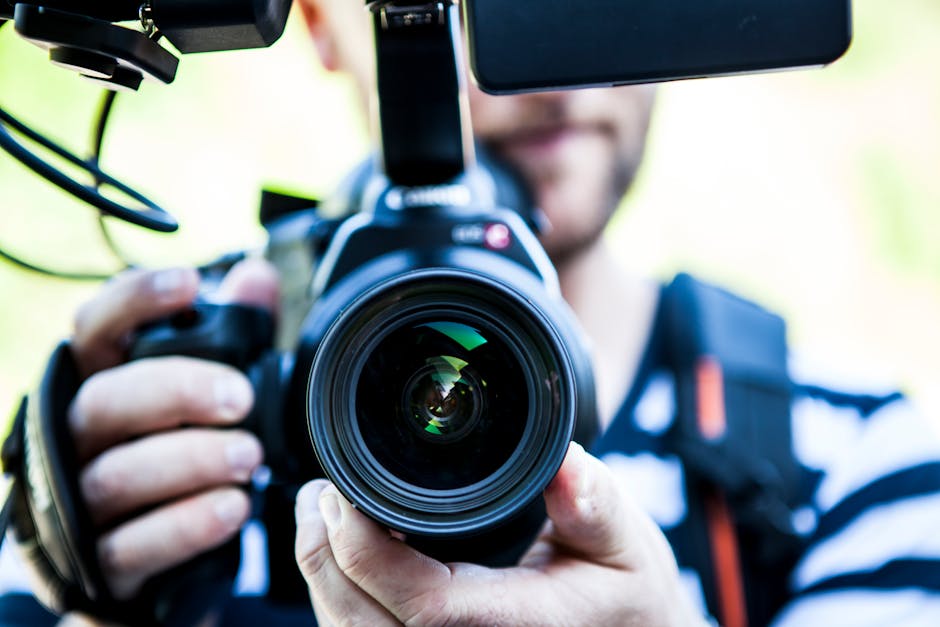 Um youtuber filmando de perto, focando na lente da câmera e equipamentos.